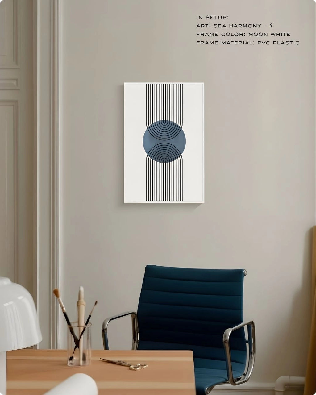 Sea Harmony 1 abstract wall art by K2C Co. featuring a deep blue circle and black geometric lines in a Moon White frame, displayed in a minimalist office setting with a blue desk chair.